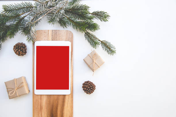 istock Christmas desk table top overhead space layout to left tablet red isolated for insert postcard Festival or picture on plane wood near have gift and pine 1245857258