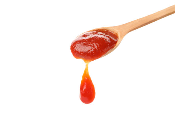 istock Wooden spoon with tomato sauce isolated on white background 1245858857