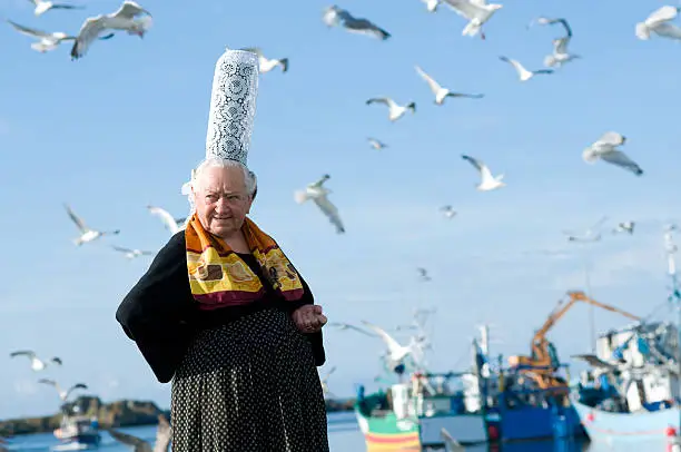 breton women with headdress in brittany posing on a harbor