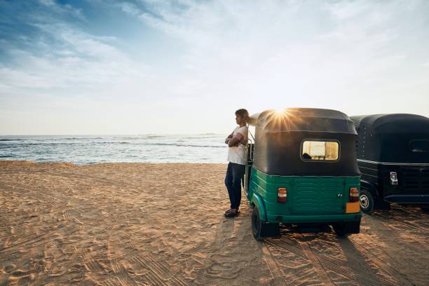 Tuk Tuk driver in Sri Lanka Tuk tuk driver waiting for passenger against sand beach and sea. Unawatuna, Sri Lanka. taxi sri lanka stock pictures, royalty-free photos & images