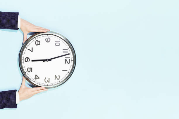 istock Business woman hands hold wall clock on pastel blue background 1245883186