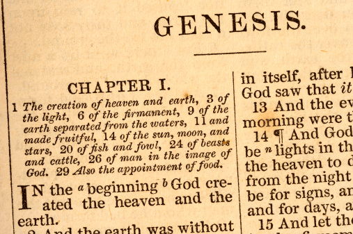 Close up of the first page of an old yellowing bible with the words of Genesis