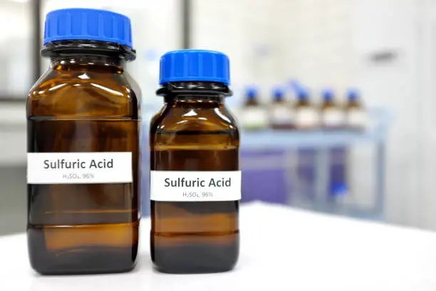 Photo of Strong sulfuric acid chemical in brown amber glass bottle inside a laboratory with copy space.