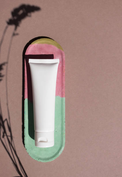 istock Mockup white plastic container for cosmetic product on brown background with trendy herbs shadow and copy space top view, above. Tube for cream, moisturizer, lotion, facial cleanser on colorful concrete decor plate 1245926034