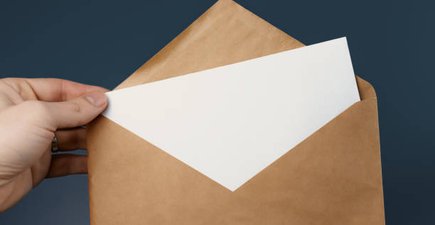 istock Cropped view of man holding craft envelope with blank white card on blue background 1245984674