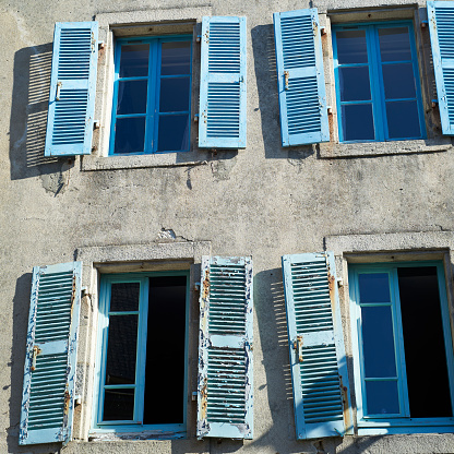four old blue windows with cracked paint on window shutter