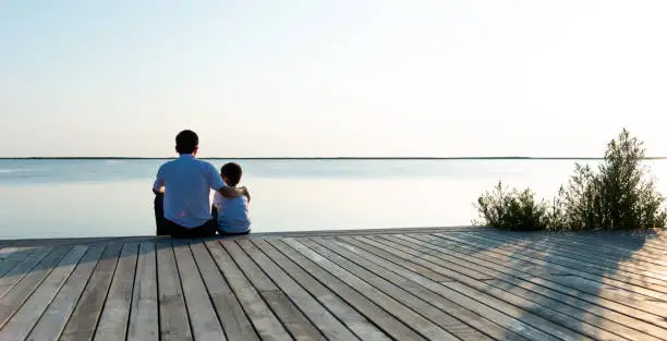 Photo of Father with his son enjoying lake view