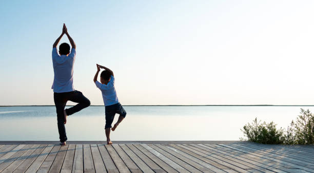 istock Father with his son doing yoga by the lake 1245986953