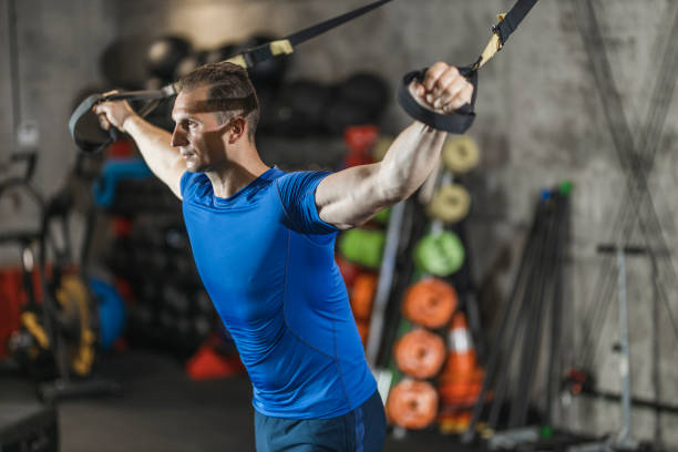 istock Man performing training in gym. Muscular guy doing exercise with elastic rope 1245986978