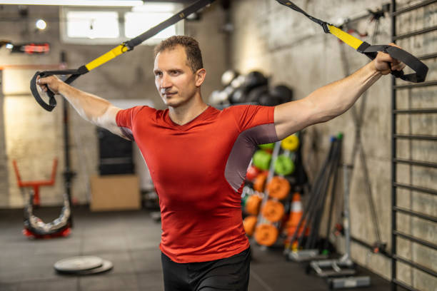 istock Man performing training in gym. Muscular guy doing exercise with elastic rope 1246006453
