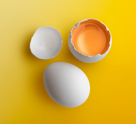 Chicken egg cracked open on yellow background