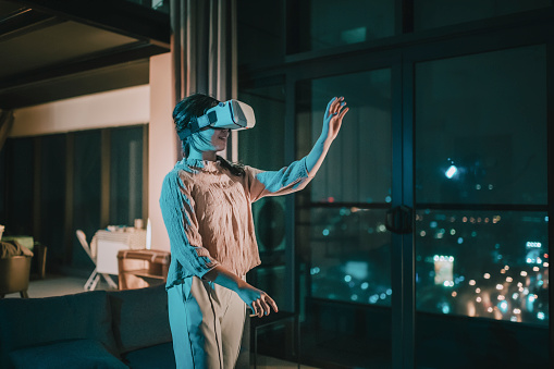 Una adolescente china asiática se puso gafas de realidad virtual y experimentar la experiencia de juego virtual 3D en la sala de estar photo