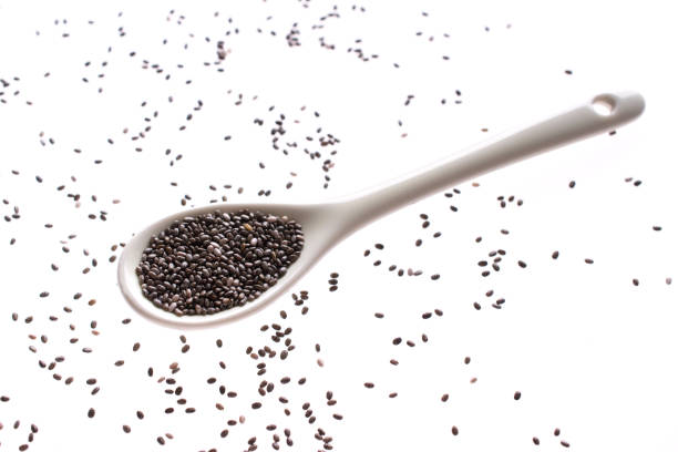 Chia seeds in white ceramic spoon isolated with white background