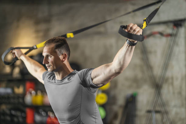 istock Man performing training in gym. Muscular guy doing exercise with elastic rope 1246029781
