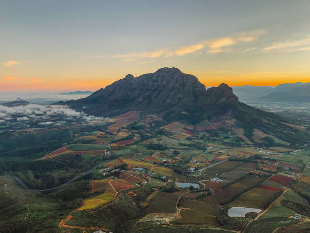 Beautiful Mountain autumn rural scene at Dawn A Cape Winelands landscape autumn scenics image at sunrise dawn.  Simonsberg can be seen surrounded by agricultural rural land in warm autumn colours close to Stellenbosch. fynbos photos stock pictures, royalty-free photos & images