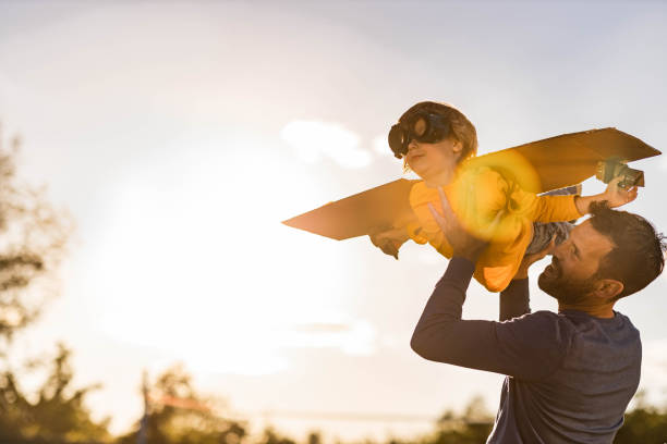 Daddy, I'm an airplane! Happy single father having fun with his small boy who is pretending to be an airplane in nature. Copy space. arms outstretched photos stock pictures, royalty-free photos & images