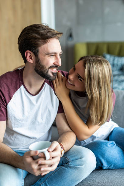 istock Beautiful young couple drink coffee hold cup, sitting on a sofa 1246074690