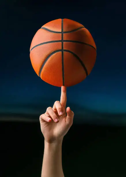 Photo of Close up of professional basketball player spinning a ball on hand finger. Street basketball athlete training for competition
