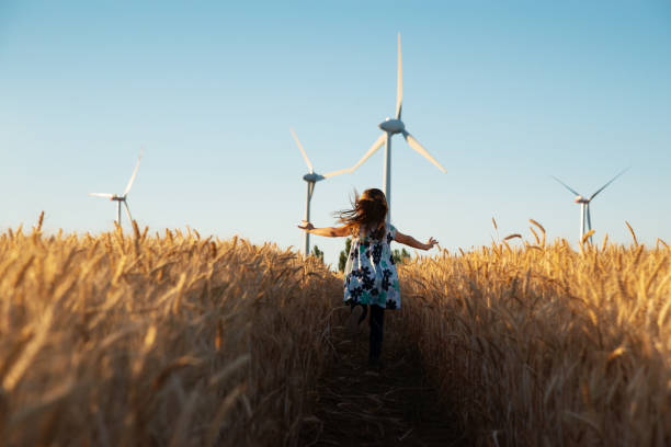 女の子は風のエネルギーへの道を実行しています - alternative energy wind turbine environment energy ストックフォトと画像