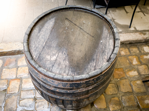 Closeup photo of old wooden barrel standing on street after rain