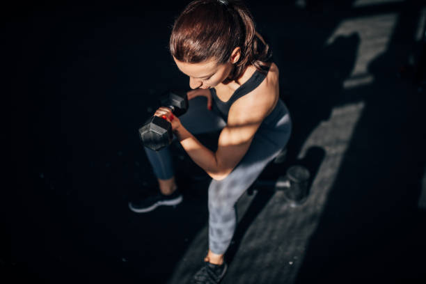 istock Fit young woman training with dumbbell in gym 1246149996