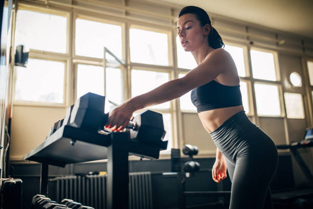 istock Fit young woman training with dumbbell in gym 1246151104