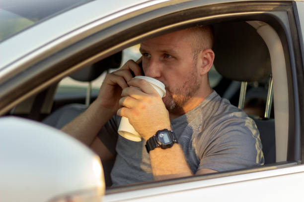 istock Smiling man drinking coffee from cup and driving car. 1246151670