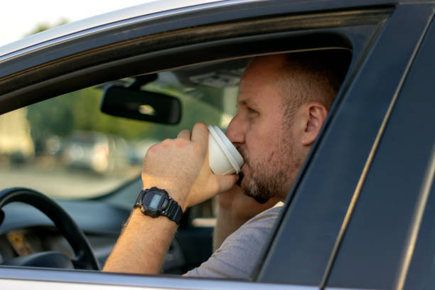 istock Smiling man drinking coffee from cup and driving car. 1246152775