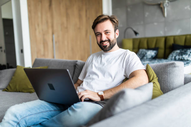 istock Handsome young man working on his laptop while relaxing on the sofa at home 1246152777