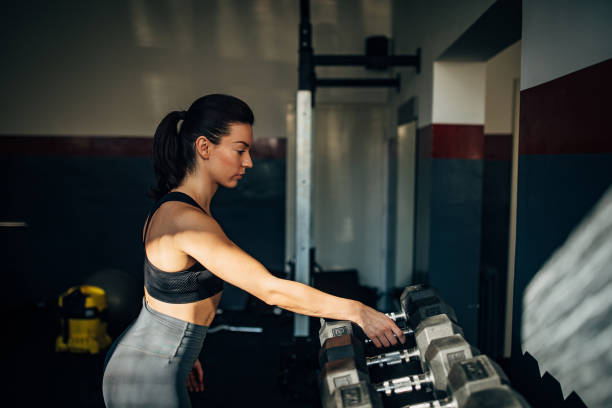 istock Fit young woman training with dumbbell in gym 1246153298
