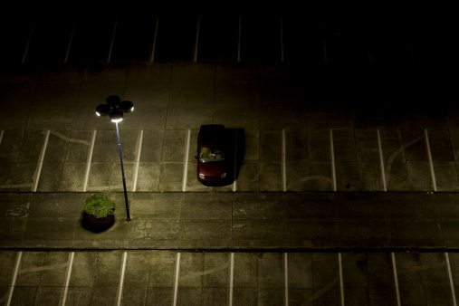 nightshot of a desolate parking lot (note: car has been altered for licence plate and logo)