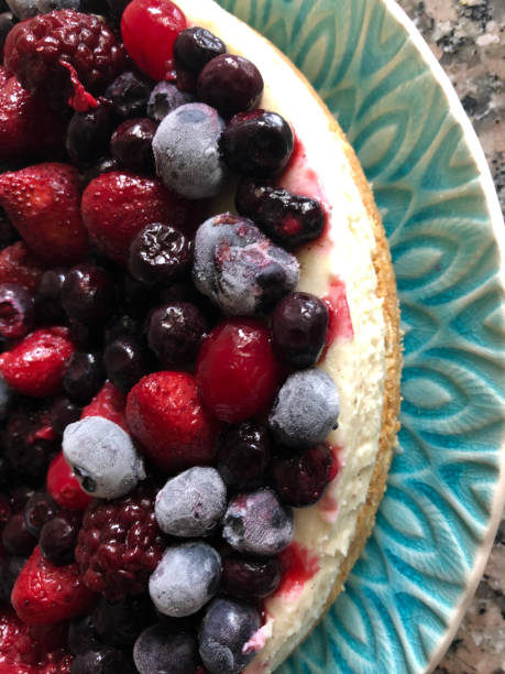 istock Image of frozen, summer fruit cheesecake with buttery biscuit base on patterned blue plate, vanilla mascarpone cream cheese dessert pudding topped with frozen strawberries, raspberries, blackcurrants and blueberries, elevated view 1246171208
