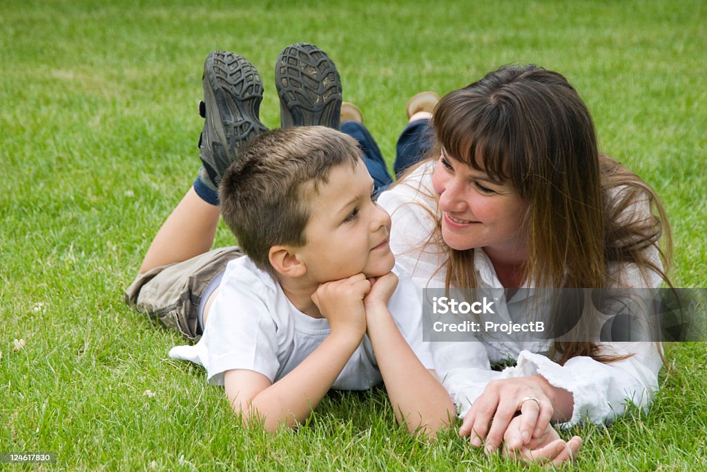 Mother and son on the grass young child with mother resting and talking on the grass in a park. Boy looking into mothers eyes. 25-29 Years Stock Photo