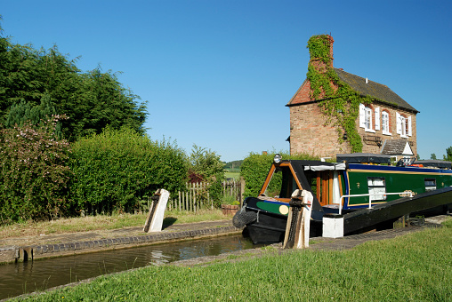 Canal Boat passing through a Lock with Lock Keepers house.
