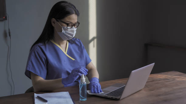 istock Doctor wipes with napkin the computer keyboard. Woman cleans the working surface with a disinfectant liquid or solution. Disinfection concept. Virus outbreak concept 1246210687