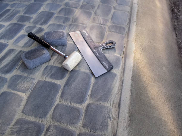 el mazo de goma blanca y una gran espátula de construcción se encuentran en la superficie de una losa de pavimentación gris recién colocada con un borde de hormigón - rubber mallet fotografías e imágenes de stock