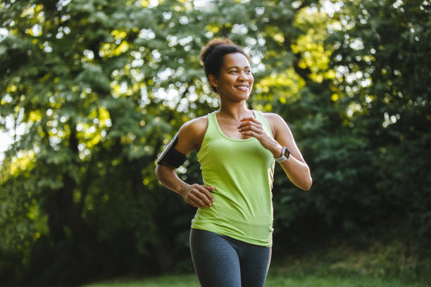 Mid adult African athletic woman jogging in nature stock photo