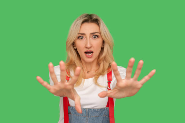 No, I'm afraid! Portrait of frightened shocked adult woman in overalls panicking and gesturing stop No, I'm afraid! Portrait of frightened shocked adult woman in overalls panicking and gesturing stop, looking freaked out, scared of horror, phobia. indoor studio shot isolated on green background Phobia stock pictures, royalty-free photos & images