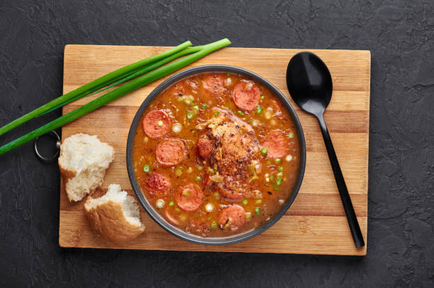 huhn und wurst gumbo suppe in schwarzer schüssel auf dunklem schiefer hintergrund. gumbo ist louisiana cajun cuisine suppe mit roux. amerikanische usa lebensmittel. traditionelle ethnische mahlzeit - chicken gumbo stock-fotos und bilder