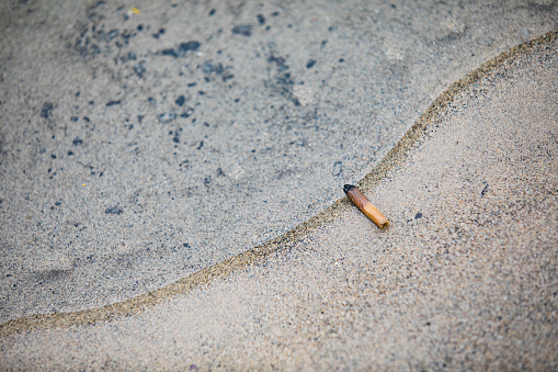 Cigarette Butt on Coastline at Water's Edge.