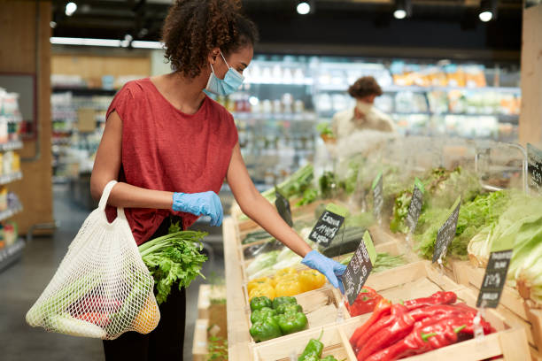 en millenial kund väljer grönsaker i en livsmedelsbutik. - organic bag bildbanksfoton och bilder