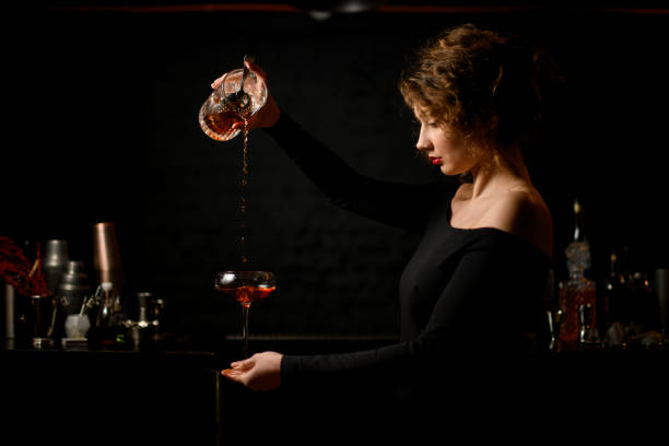 sexy woman at bar masterfully pours drink into glass