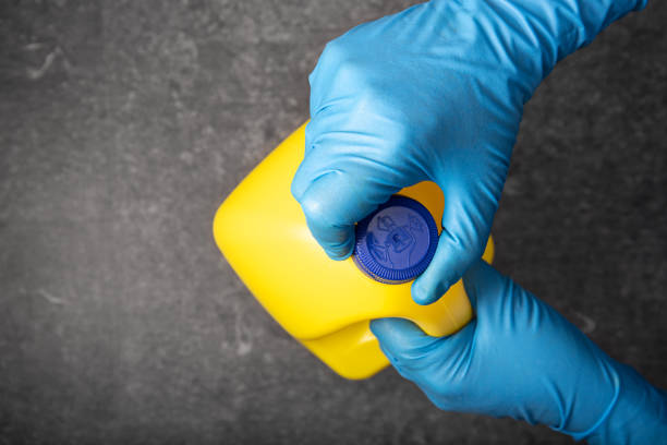 Human hand in protective glove opening a bleach bottle Human hand in protective glove opening a yellow bleach bottle. Disinfection concept bleach stock pictures, royalty-free photos & images