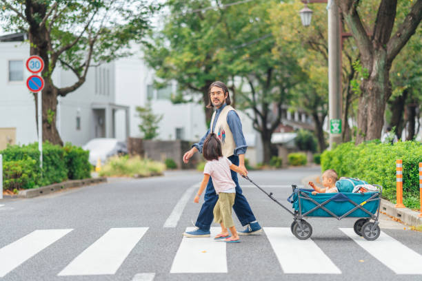 padre llevando a sus hijos a caminar por el barrio - familia de cruzar la calle fotografías e imágenes de stock