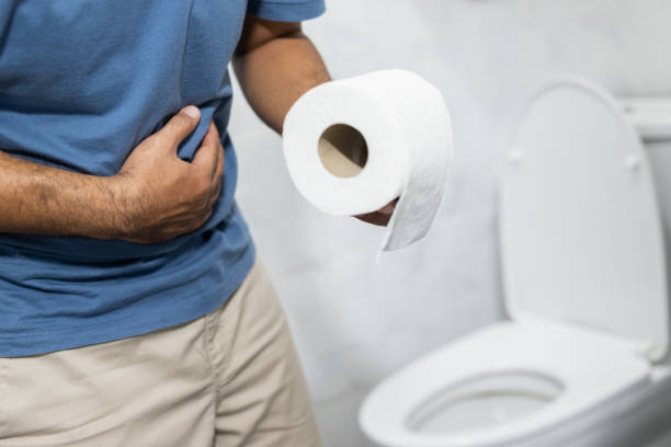 un homme a la diarrhée il est ensuite allé aux toilettes pour prendre les numéros deux. dans sa main, il avait du papier de soie à laver et à nettoyer. - wash bowl photos et images de collection