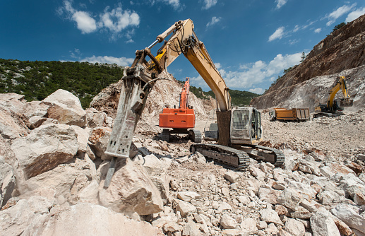 Hydraulic crawler excavator extracting stone in quarry at work