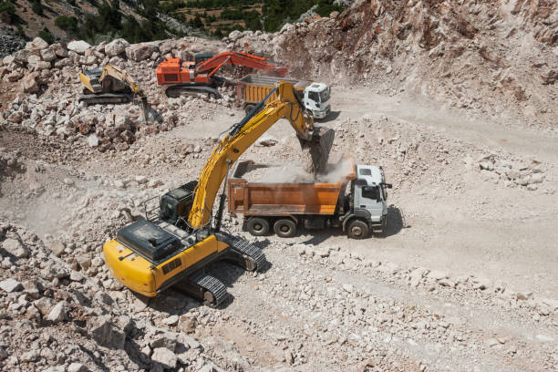 excavadoras y camiones pesados trabajando en obra - rock quarry fotografías e imágenes de stock