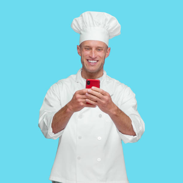 istock Caucasian male chef standing in front of blue background wearing pants and using text messaging 1246294518