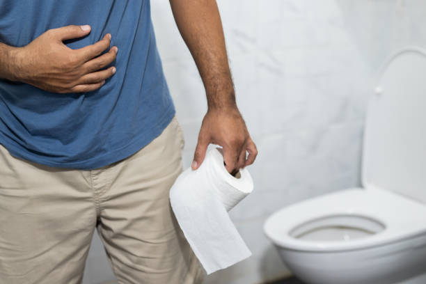 un homme a la diarrhée il est ensuite allé aux toilettes pour prendre les numéros deux. dans sa main, il avait du papier de soie à laver et à nettoyer. - wash bowl photos et images de collection