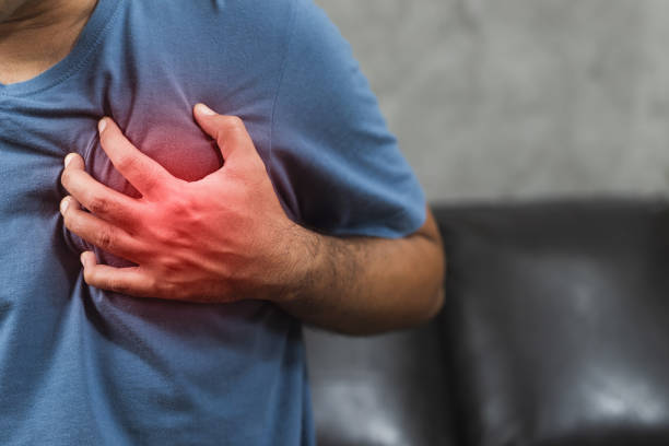 рука человека в грудь, сжимая его сердце у него был внезапный сердечный приступ. - human hand help pain heart attack стоковые фото и изображения